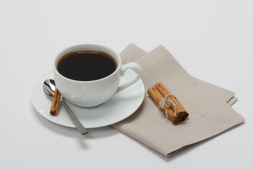 Black Coffee In White Cup And Cinnamon Sticks On Folded Natural
