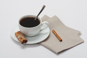 Black Coffee In White Cup And Cinnamon Sticks On Folded Natural