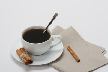 Black Coffee In White Cup And Cinnamon Sticks On Folded Natural