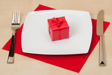 Red Gift Box On White Plate. Wooden Table