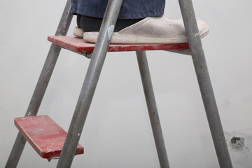 House Renovation. Master in the uniform on the ladder repairing room interior