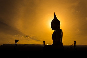 Silhouette buddha statue in sunset background.