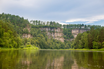Tourist route to the Urals. Pine forest on a cliff with views of the calm rive Hay