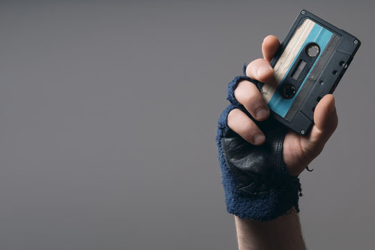 male hand with glove holding an old music tape