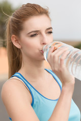 Junge Sportlerin trinkt Wasser aus der Flasche