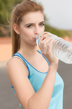 Junge Sportlerin trinkt Wasser aus der Flasche