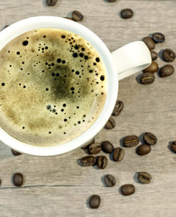 Cup of hot drink with coffee beam on wooden table, close