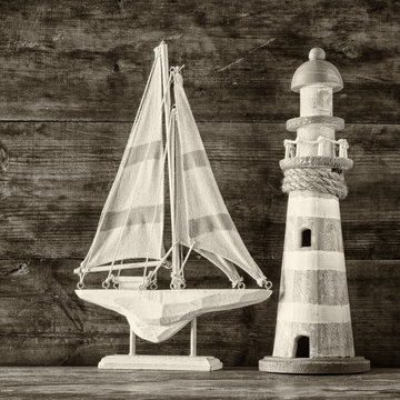 old vintage wooden lighthouse and sailing boat on wooden table