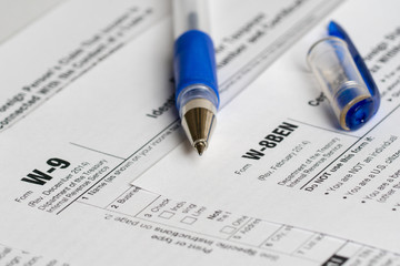 tax reporting forms with opened blue pen