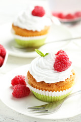 Raspberry cupcakes on plate on white wooden background