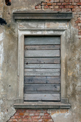 Old, boarded up window in the ruined wall of an old manor house in Poland.