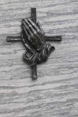 Betende Hände mit Kreuz auf einem Grabstein
