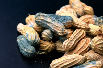 heap of moldy peanuts on a black background