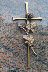 Bronzene Rose mit Kreuz auf Grabstein