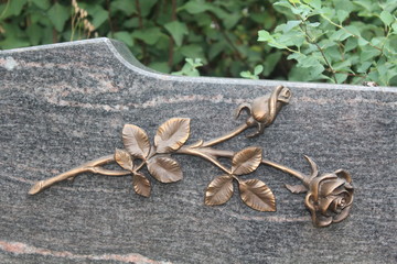 Bronzene Rose auf Grabstein