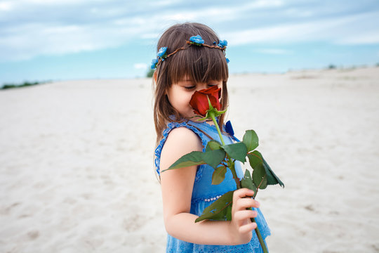  little girl playing with rose flowers at the beach