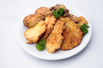 Breaded pork chops and chicken legs on plate