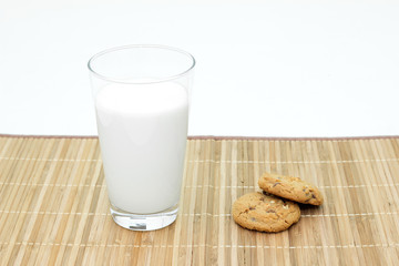 Cookies and a glass of milk on a bamboo table cloth