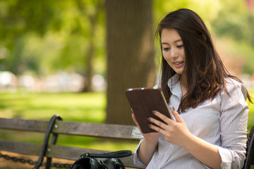 Obraz premium Young Asian woman in city using tablet computer
