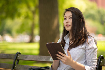 Obraz premium Young Asian woman in city using tablet computer