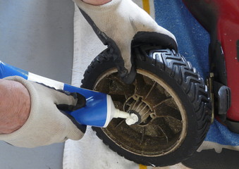 Man Greasing Lawn Mower Wheel