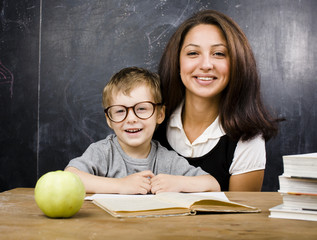 little cute boy in glasses with young real teacher, classroom