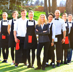 Large group of waiters and waitresses standing in row.