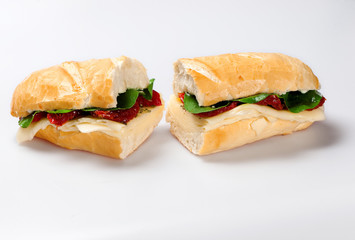 Sandwich on a white plate with turkey breast, tomato and lettuce.