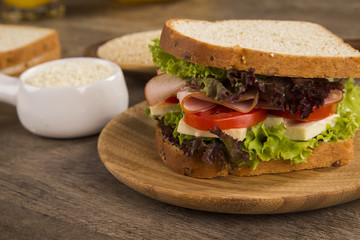Sandwich on a white plate with turkey breast, tomato and lettuce.