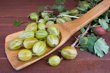 Fresh berries of red and green gooseberries with leaves on the old wooden table