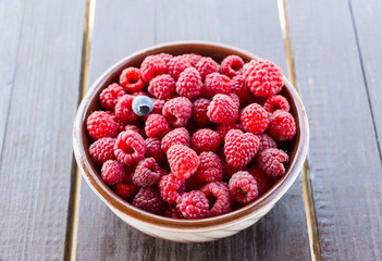 Fresh raspberries in plate on a wooden table