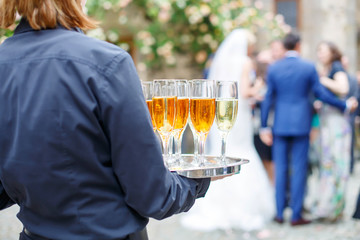 Waitress with dish of champagne and wine glasses