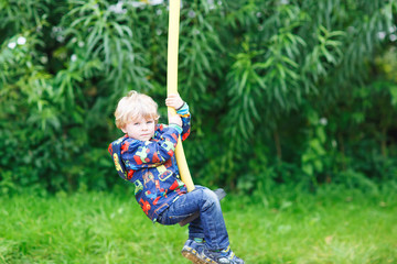 Little smiling boy of three years having fun on swing