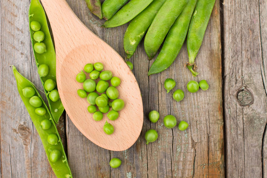 Freshly picked green peas on a wooden table.