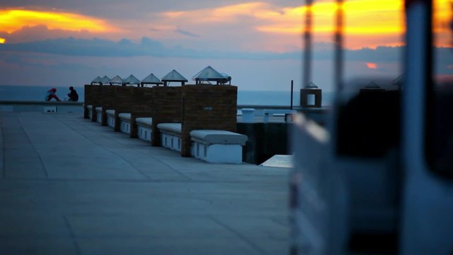 Golf car rides on the pier at sunset and a couple love sitting