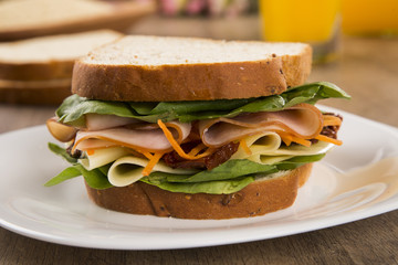 Sandwich on a white plate with turkey breast, tomato and lettuce