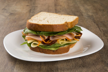 Sandwich on a white plate with turkey breast, tomato and lettuce