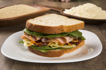 Sandwich on a white plate with turkey breast, tomato and lettuce