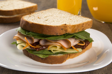 Sandwich on a white plate with turkey breast, tomato and lettuce