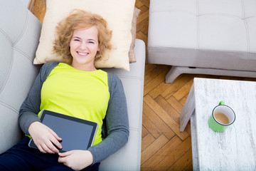 Junge Frau mit Tablet PC auf dem Sofa	