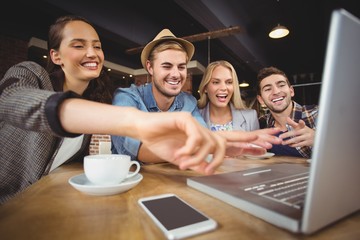 Laughing friends looking at laptop and pointing at screen