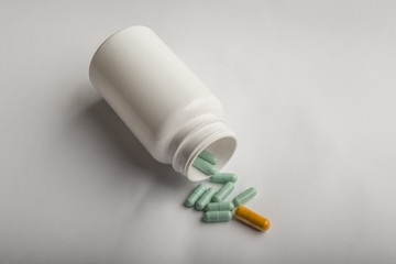 Colorful pills and pill bottle on white background