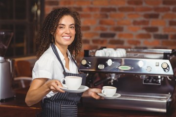 Smiling barista holding two cups of coffee - obrazy, fototapety, plakaty