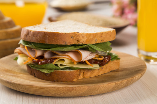 Sandwich on a white plate with turkey breast, tomato and lettuce