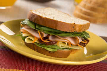 Sandwich on a white plate with turkey breast, tomato and lettuce