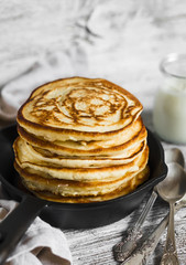 pancakes with honey in a pan on a light wooden background