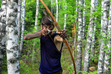 Молодой человек в лесу с луком и стрелами