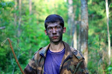 Obraz premium Молодой человек в лесу с луком и стрелами