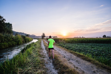 Ragazzo che corre all'alba su strada di campagna in estate