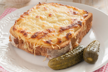 Croque Monsieur a French grilled cheese and ham sandwich served with pickles